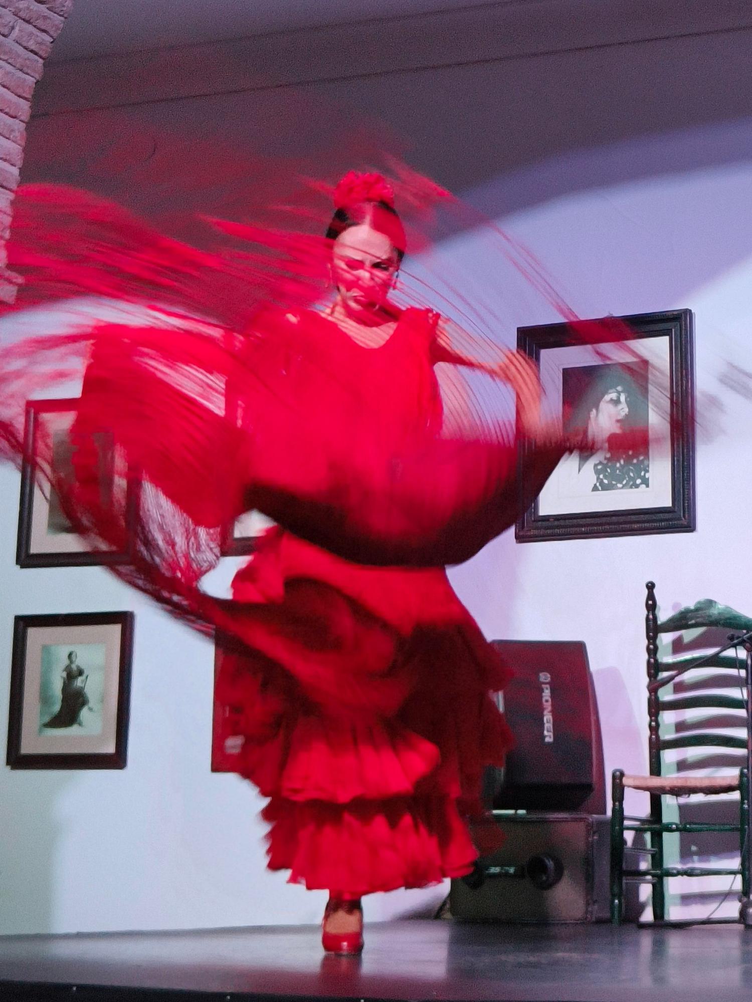 Escena de flamenco en sala pequeña, movimiento, luz dramática, sin tópicos.